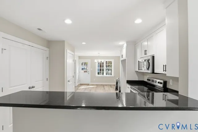 a view of kitchen with stainless steel appliances granite countertop a sink and a stove top oven with wooden floor