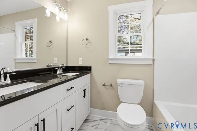 a bathroom with a granite countertop toilet sink and mirror