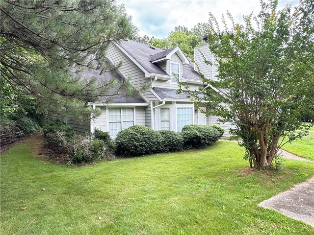 a view of a house next to a big yard and large trees