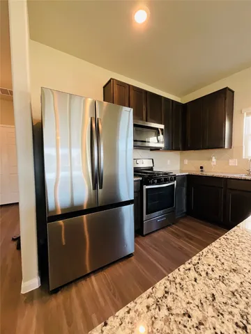 a kitchen with stainless steel appliances granite countertop a refrigerator stove and microwave