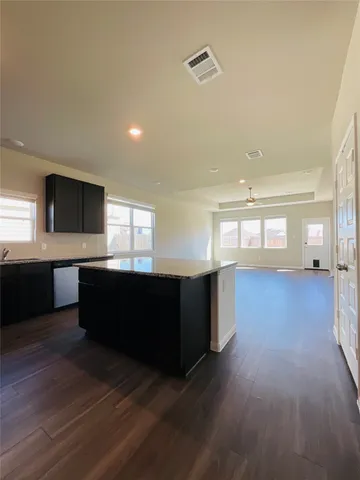 a living room with hard wood flooring and a kitchen