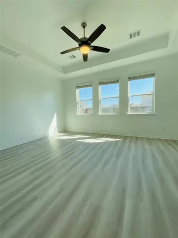 a view of empty room with wooden floor and ceiling fan