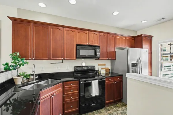 a kitchen with stainless steel appliances granite countertop a refrigerator a stove top oven a sink and dishwasher