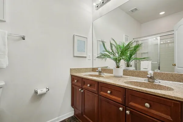 a bathroom with a granite countertop sink a mirror and a potted plant