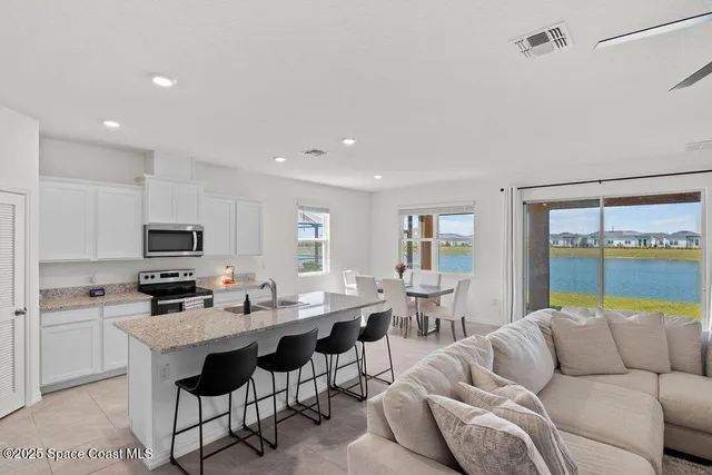 a living room with furniture kitchen view and a large window