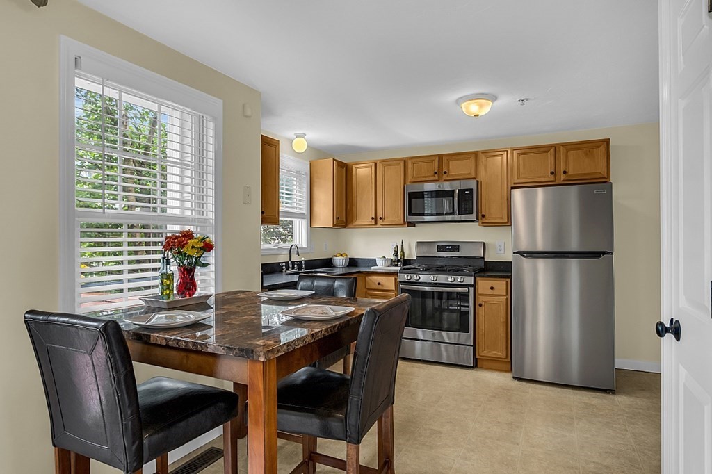 417 Hildreth Street, Unit 3 Lowell, MA 01850 - Photo 3 of 37 a kitchen with stainless steel appliances granite countertop a stove a refrigerator a stove a sink a dining table and chairs