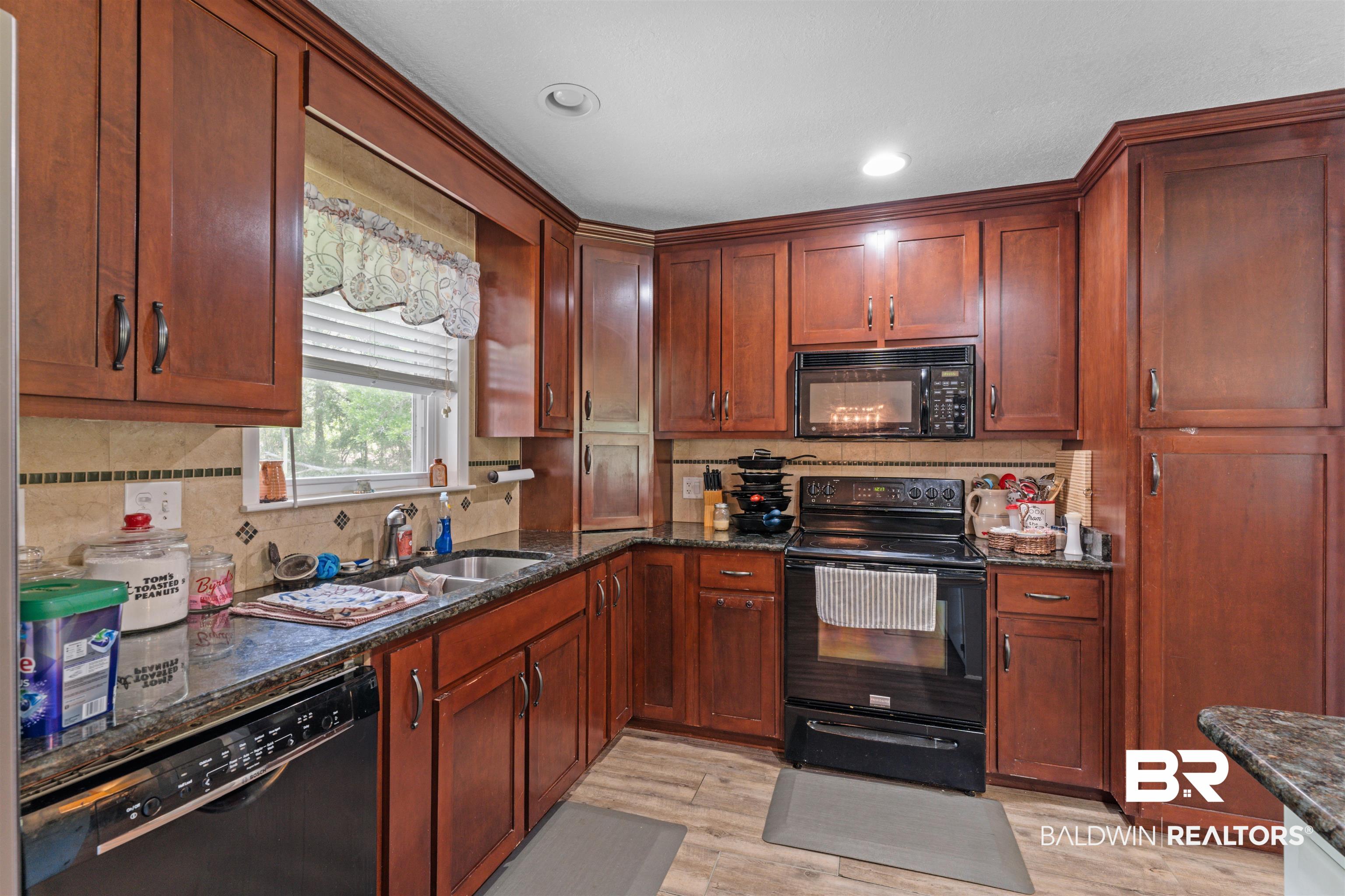 32794 Antietam Road Lillian, AL 36549 - Photo 7 of 20 Kitchen with black appliances, backsplash, light wood finished floors, dark stone countertops, and recessed lighting
