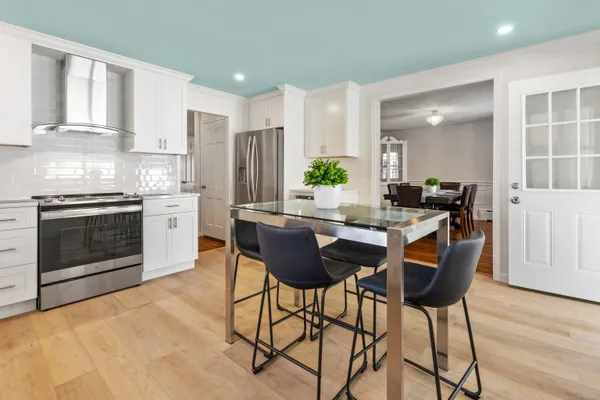 a kitchen with stainless steel appliances granite countertop a stove a refrigerator a sink a dining table and chairs