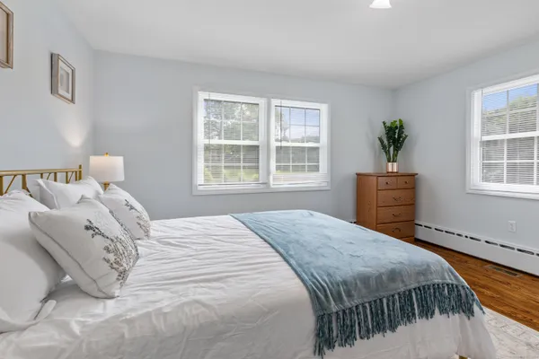 a bedroom with a bed a dresser and next to a window