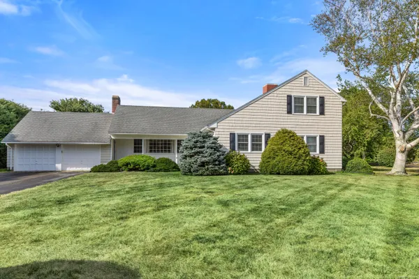 a view of a house with a big yard potted plants and large tree