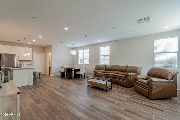 a living room with furniture kitchen view and a wooden floor