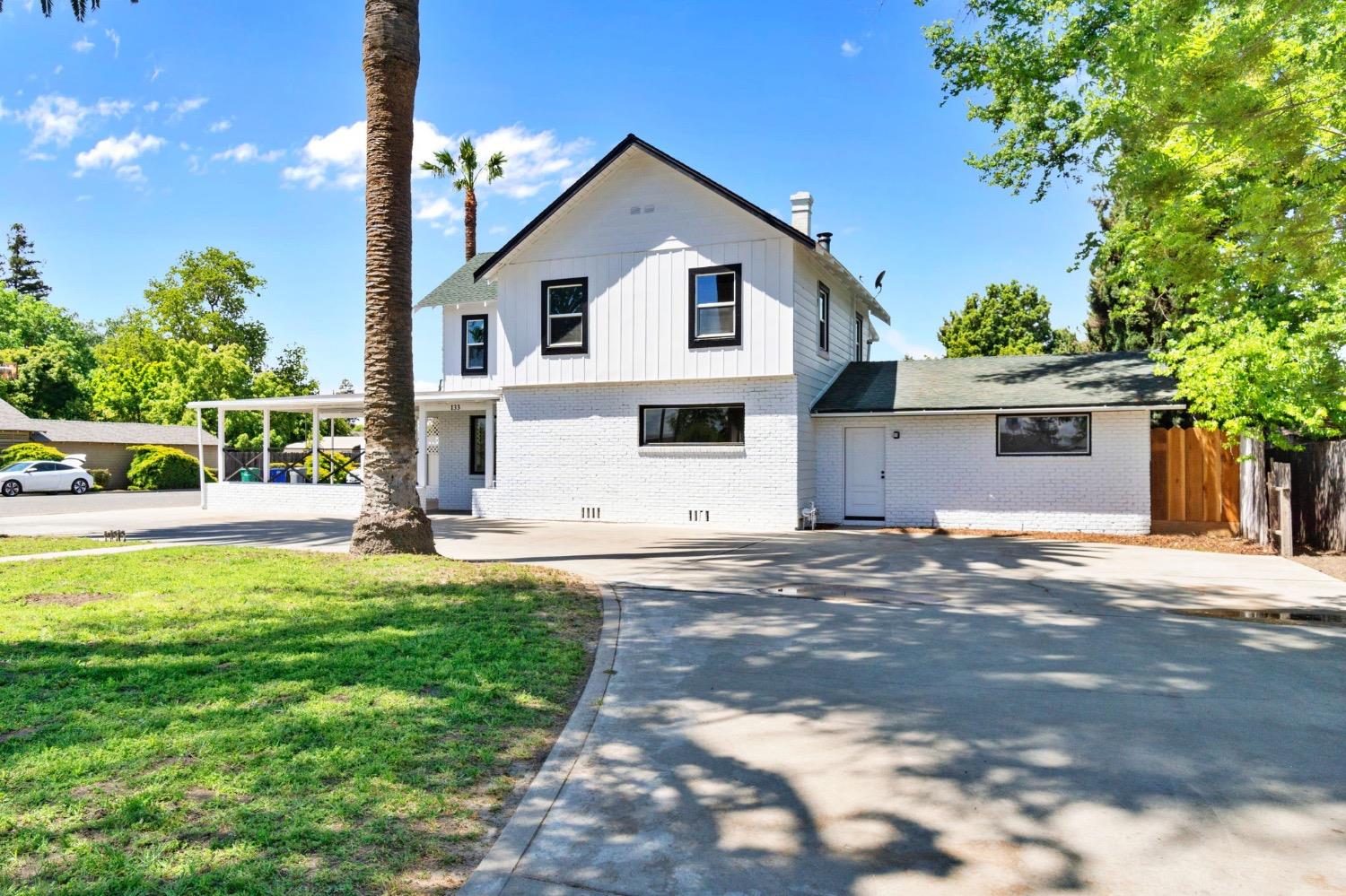 133 South Reed Avenue Reedley, CA 93654 - Photo 1 of 42 a view of a white house with a yard and large tree