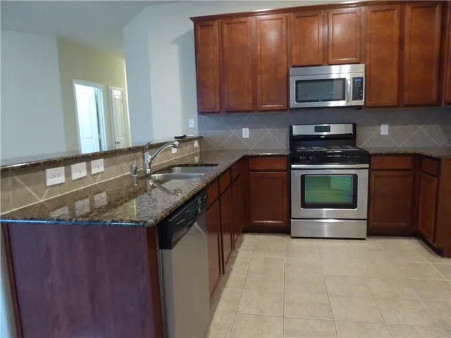 a kitchen with granite countertop a stove microwave and sink