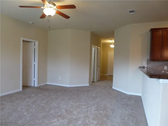a view of an empty room with a chandelier fan