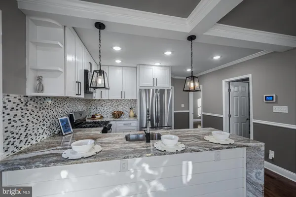 a kitchen with kitchen island granite countertop a sink and a refrigerator