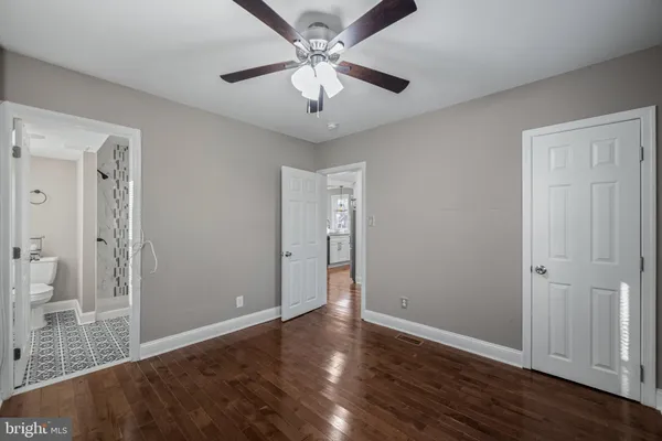 an empty room with wooden floor and ceiling fan