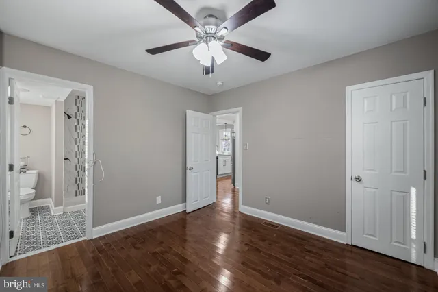an empty room with wooden floor and ceiling fan