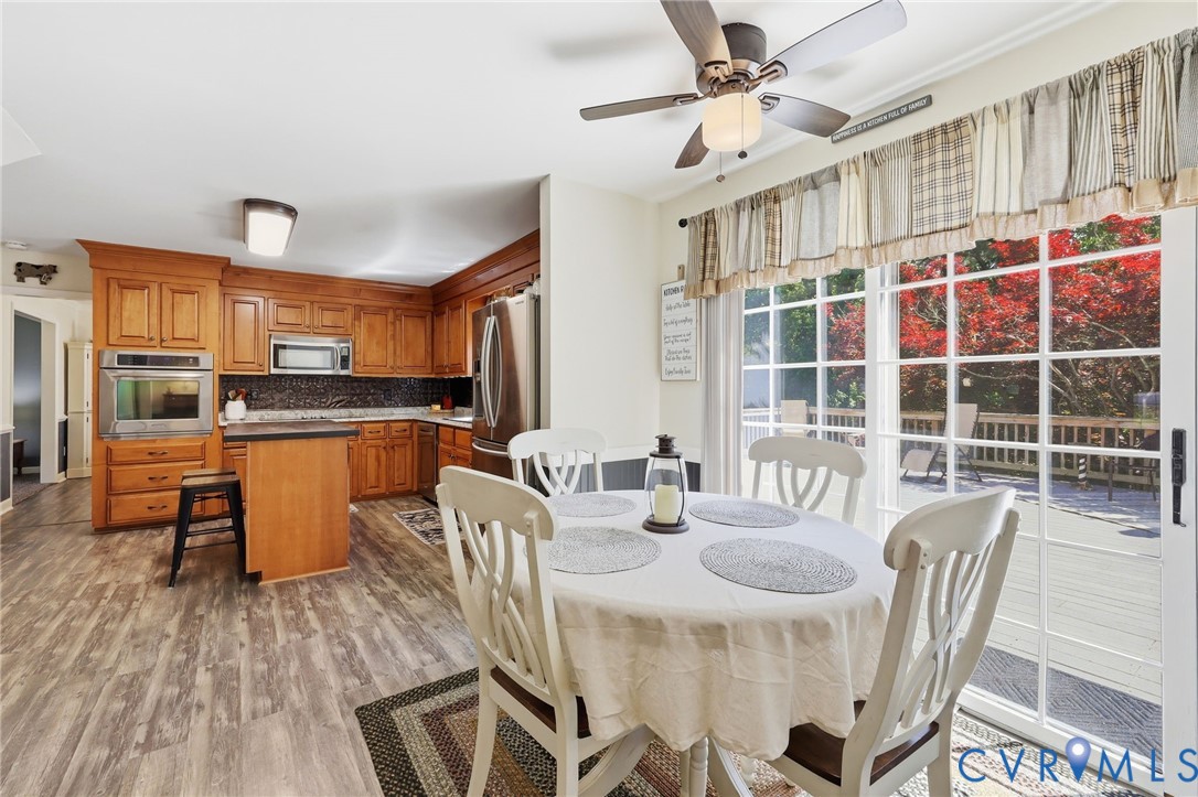 11200 Surry Road Chester, VA 23831 - Photo 20 of 48 a kitchen with stainless steel appliances granite countertop a stove a refrigerator a dining table and chairs with wooden floor