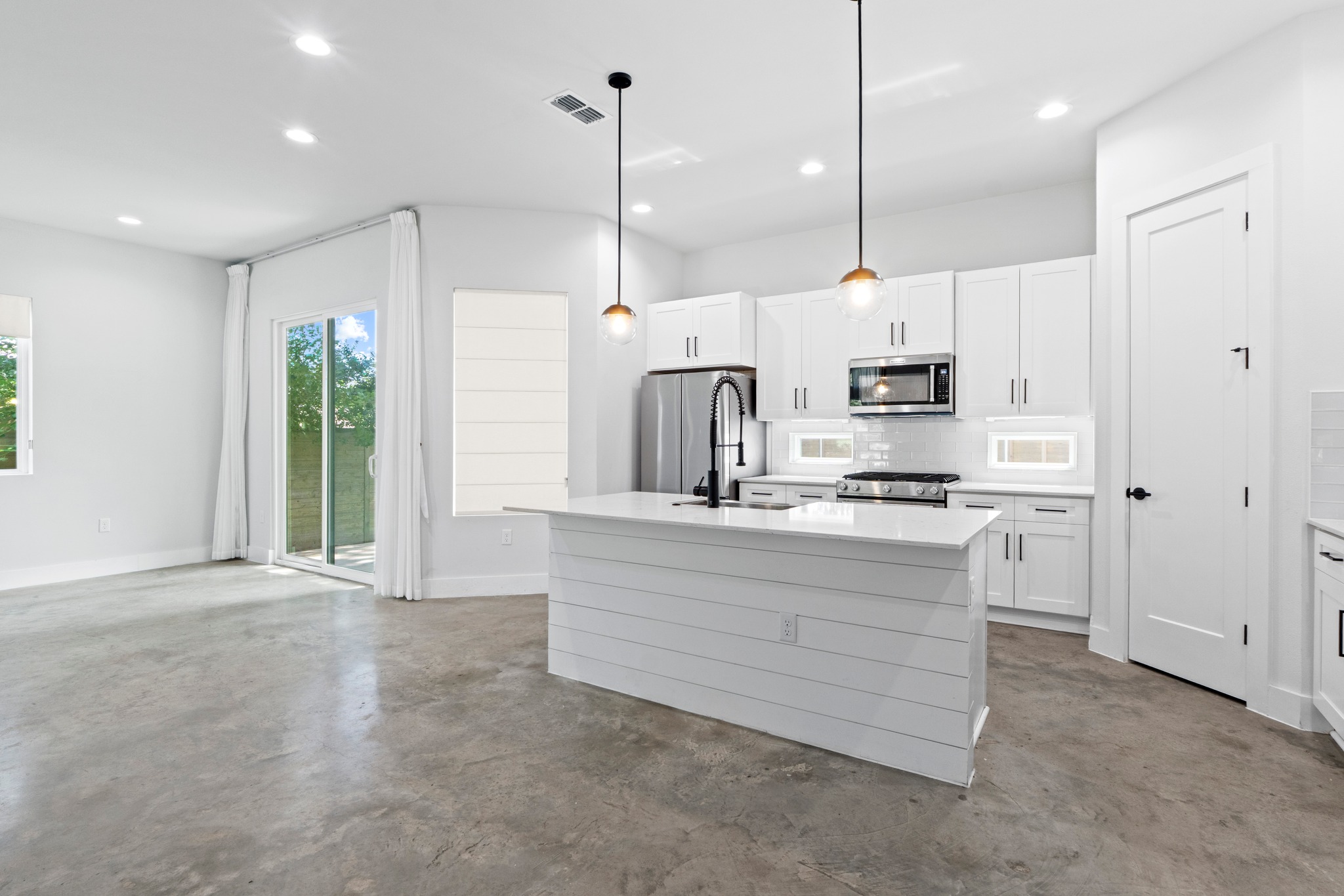 2007 Chestnut Avenue, Unit 1 Austin, TX 78722 - Photo 11 of 32 A streamlined kitchen island anchors this open-concept space, offering sleek white cabinetry and durable concrete flooring.