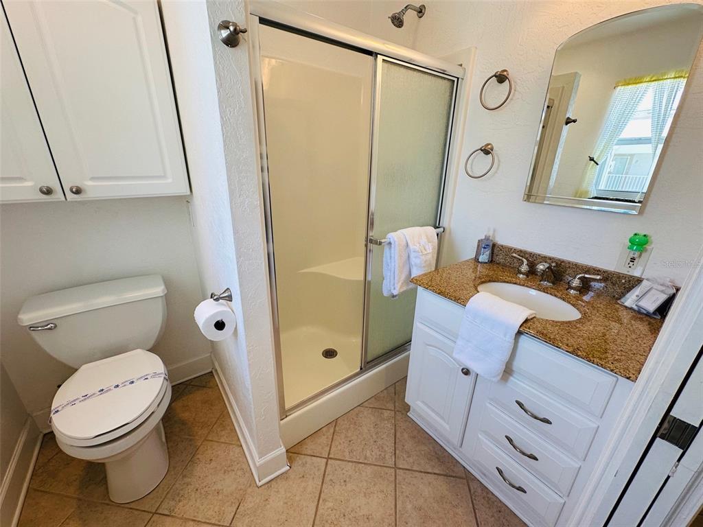 709 Gulf Way, Unit 19 St. Pete Beach, FL 33706 - Photo 32 of 39 a bathroom with a granite countertop sink toilet and shower