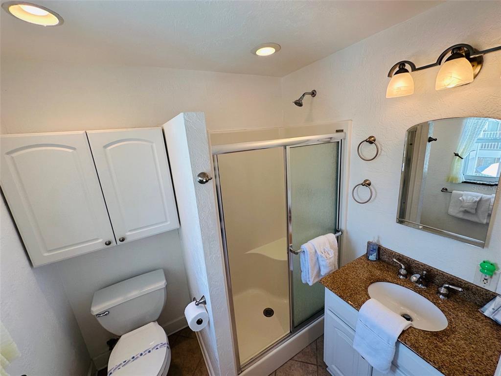 709 Gulf Way, Unit 19 St. Pete Beach, FL 33706 - Photo 34 of 39 a bathroom with a granite countertop toilet sink and mirror