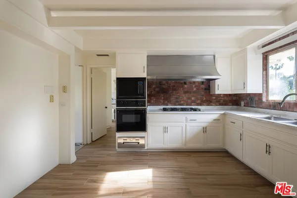 a kitchen with wooden floors white cabinets and stainless steel appliances