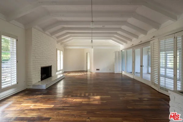 a view of a livingroom with wooden floor a fireplace and window