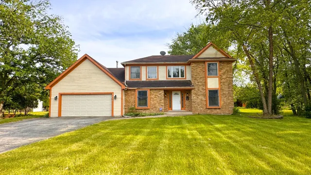 a front view of a house with a yard and trees