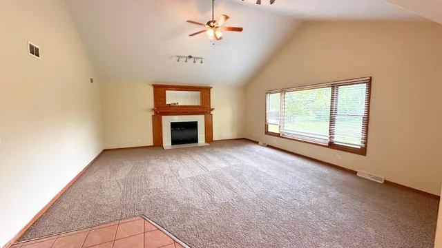 an empty room with windows and fireplace