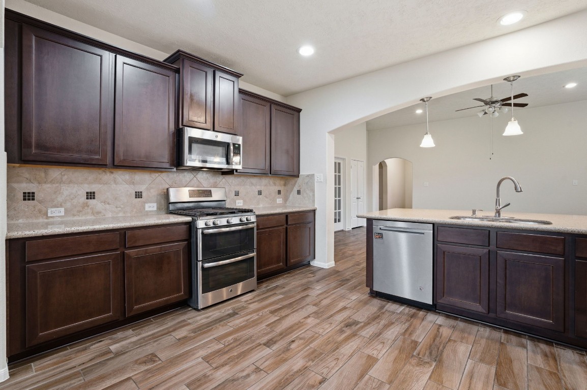 10007 Open Slope Court Humble, TX 77396 - Photo 13 of 39 a kitchen with stainless steel appliances granite countertop wooden cabinets a sink and dishwasher