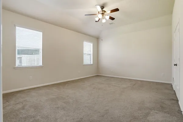 an empty room with windows and chandelier fan