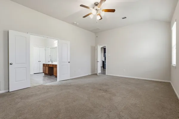 a view of a livingroom with a kitchen space and a ceiling fan