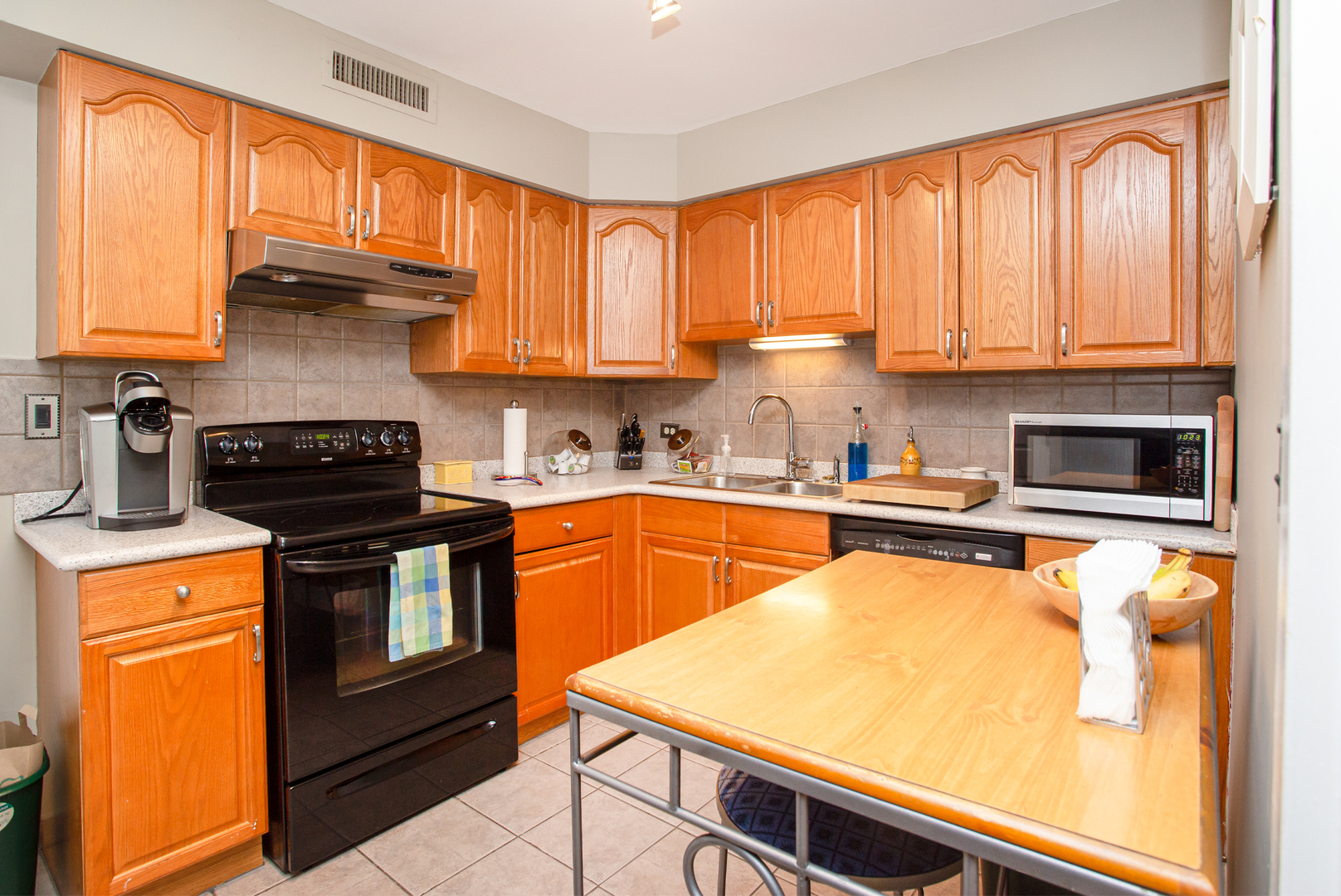 6007 North Sheridan Road, Unit 39D Chicago, IL 60660 - Photo 7 of 20 a kitchen with stainless steel appliances granite countertop a stove a sink dishwasher and a refrigerator with wooden floor