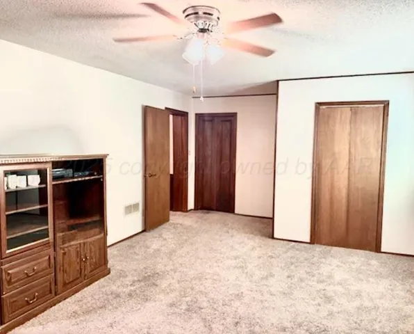 an empty room with closet and a chandelier fan