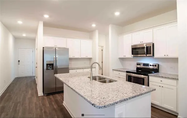 a kitchen with stainless steel appliances granite countertop a sink stove microwave and refrigerator