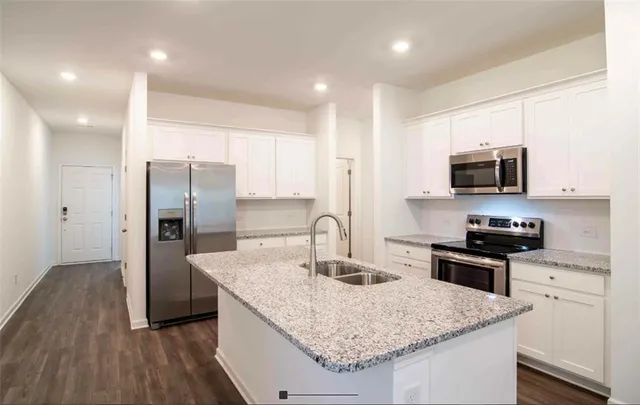 a kitchen with stainless steel appliances granite countertop a sink stove microwave and refrigerator