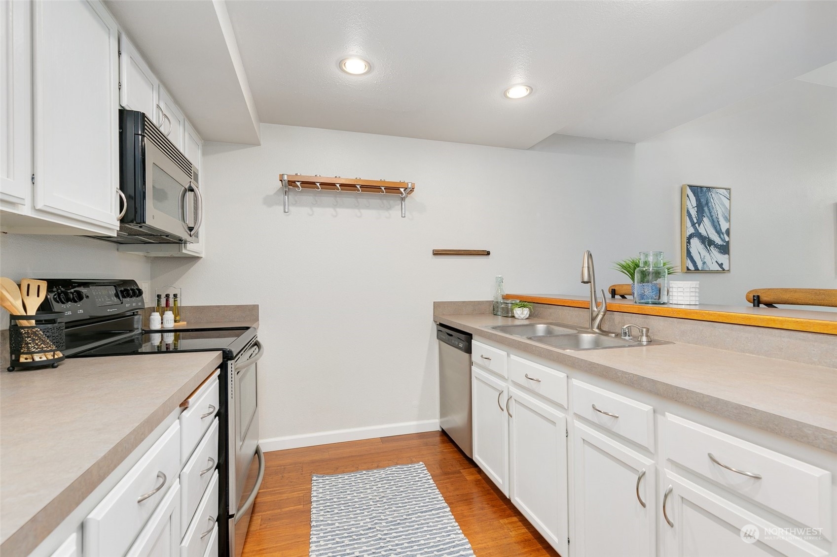 7355 Old Redmond Road, Unit 113 Redmond, WA 98052 - Photo 15 of 25 a kitchen with a sink dishwasher and white cabinets with wooden floor