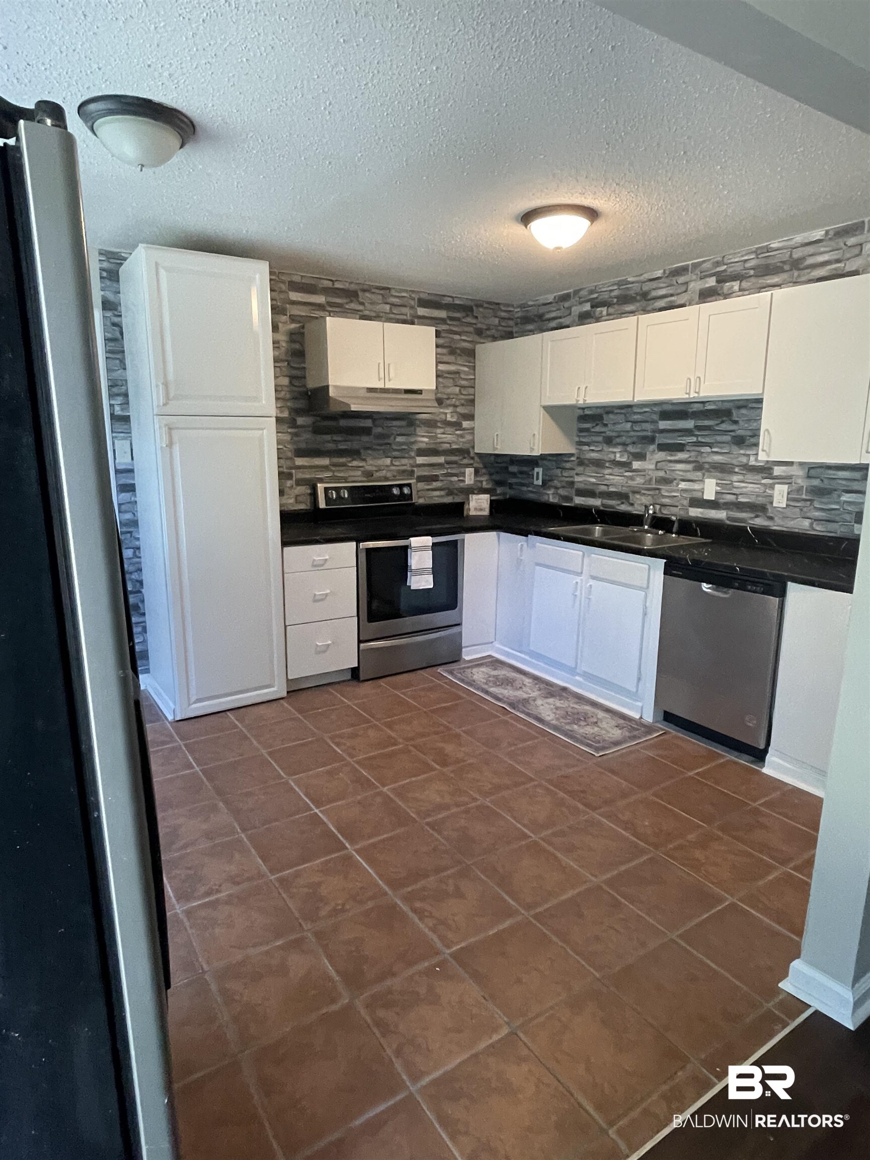 15060 Starlight Avenue Wilmer, AL 36587 - Photo 3 of 12 Kitchen with sink, a textured ceiling, white cabinetry, stainless steel appliances, and decorative backsplash