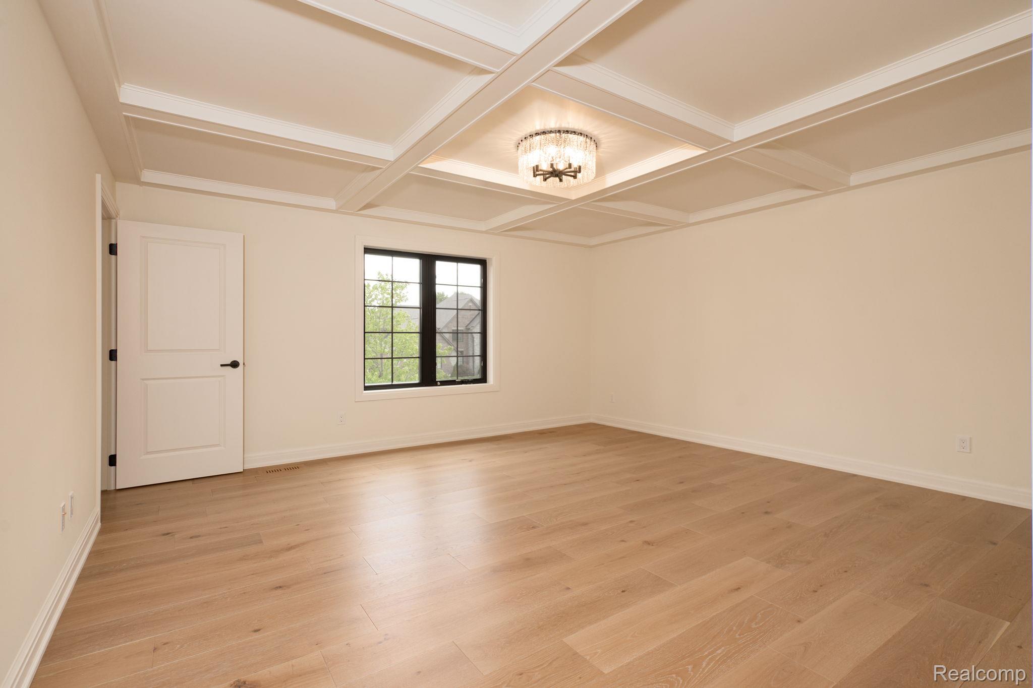 3836 Coachwood Lane Rochester, MI 48309 - Photo 68 of 82 Spacious room featuring a coffered ceiling with a central chandelier, wood-finish flooring, and a black-framed window