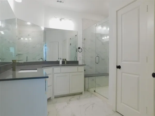 a bathroom with a granite countertop sink a mirror and shower