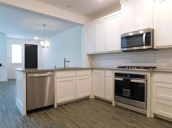 a kitchen with stainless steel appliances white cabinets and a stove top oven