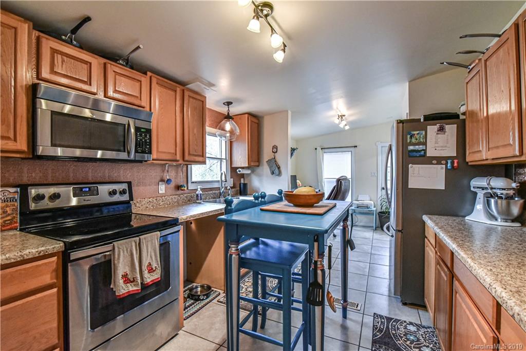 250 Mount Allen Road Black Mountain, NC 28711 - Photo 15 of 22 a kitchen with stainless steel appliances granite countertop a stove top oven a sink dishwasher a dining table and chairs with wooden floor