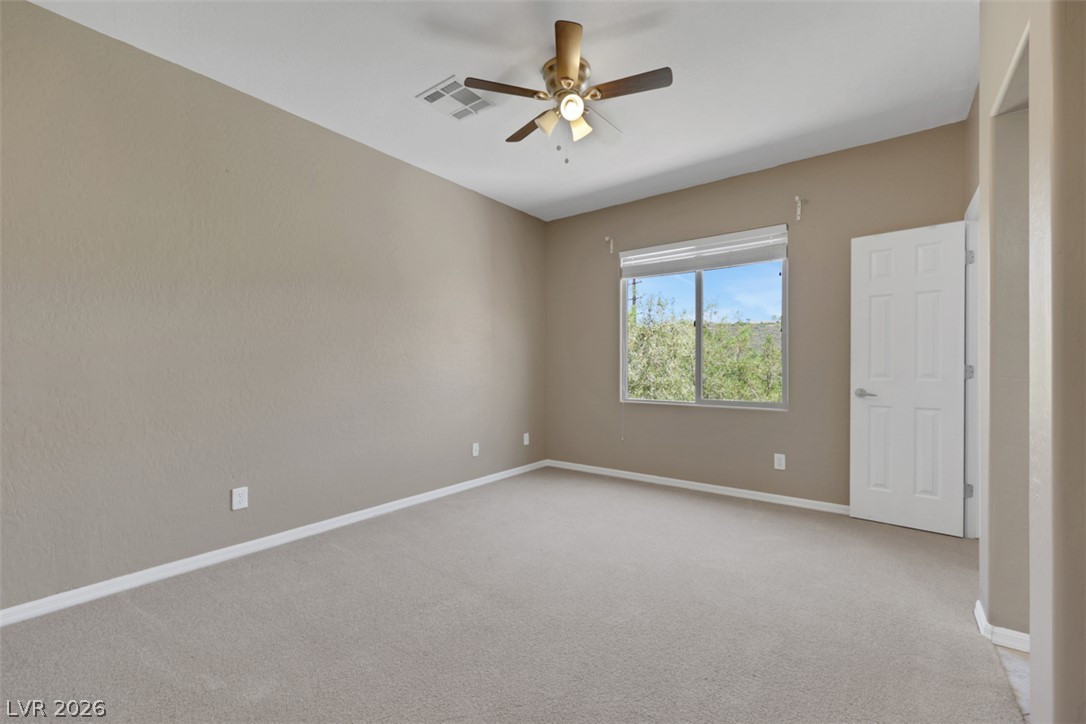 2501 Bechamel Place Henderson, NV 89044 - Photo 25 of 50 A well-lit bedroom features plush carpeting and an overhead ceiling fan.