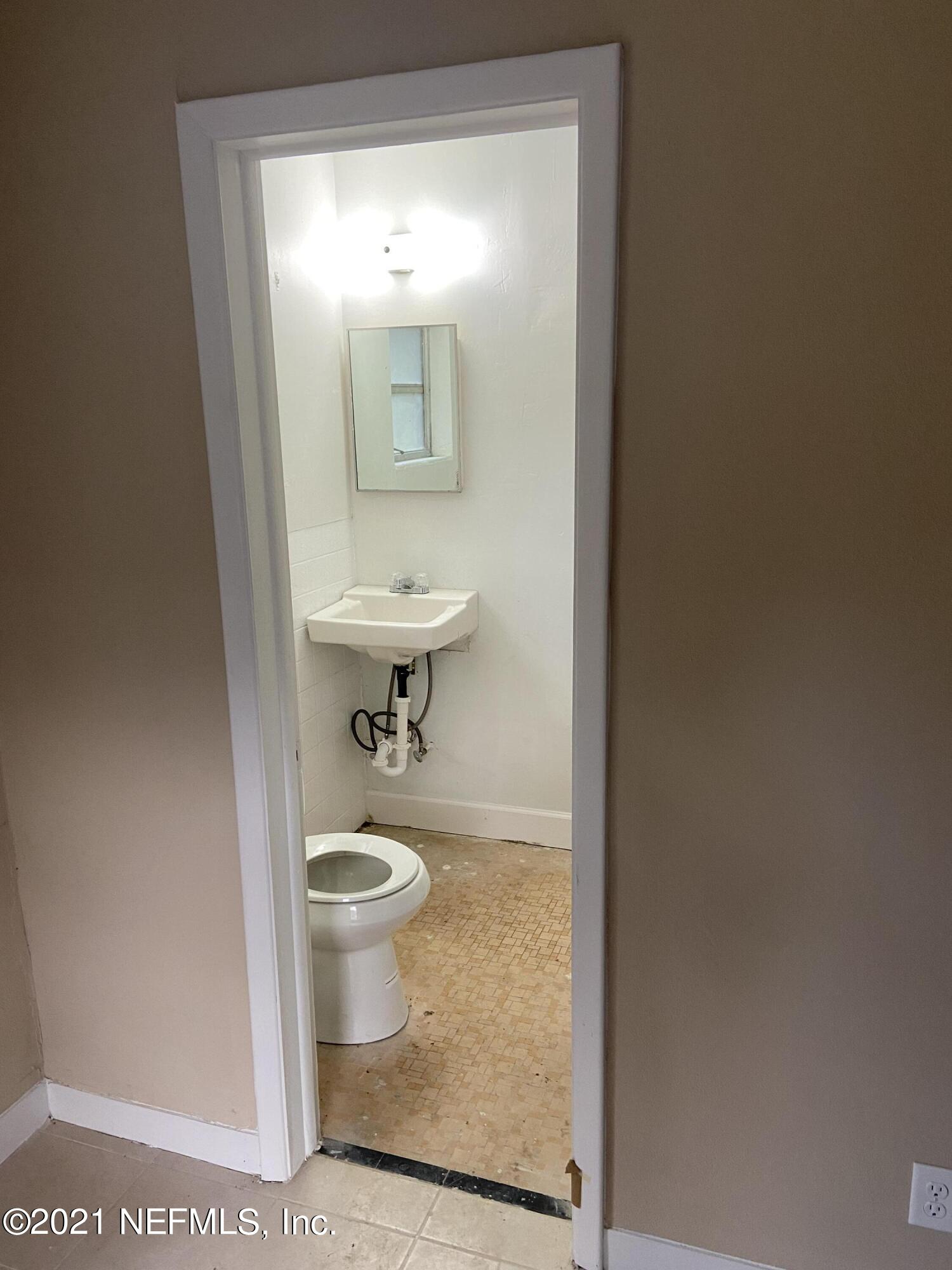 5643 Merrill Road, Unit 4 Jacksonville, FL 32277 - Photo 4 of 9 a bathroom with a sink a toilet and mirror