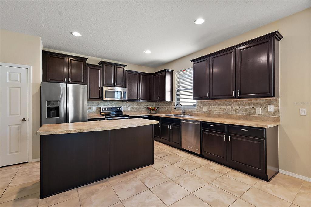 20945 Oldenburg Loop Mount Dora, FL 32757 - Photo 11 of 37 a large kitchen with stainless steel appliances granite countertop a stove a sink dishwasher and a refrigerator
