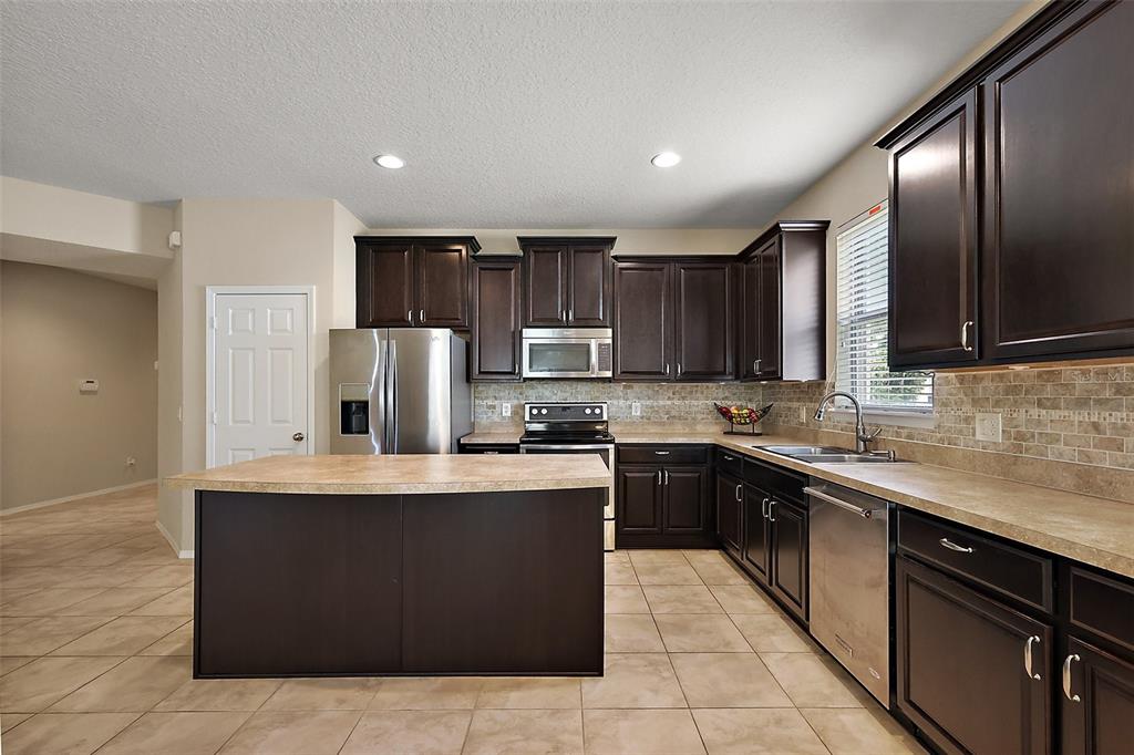 20945 Oldenburg Loop Mount Dora, FL 32757 - Photo 12 of 37 a large kitchen with stainless steel appliances granite countertop a stove a sink dishwasher and a refrigerator
