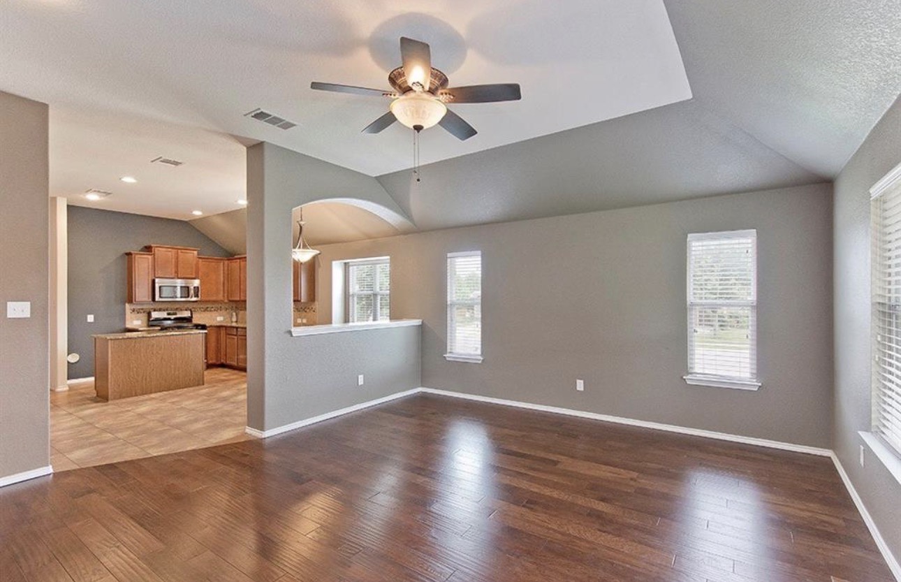 1052 Hot Spring Valley Buda, TX 78610 - Photo 12 of 36 Unfurnished living room with dark wood-style flooring, vaulted ceiling, ceiling fan, arched walkways, and a textured ceiling