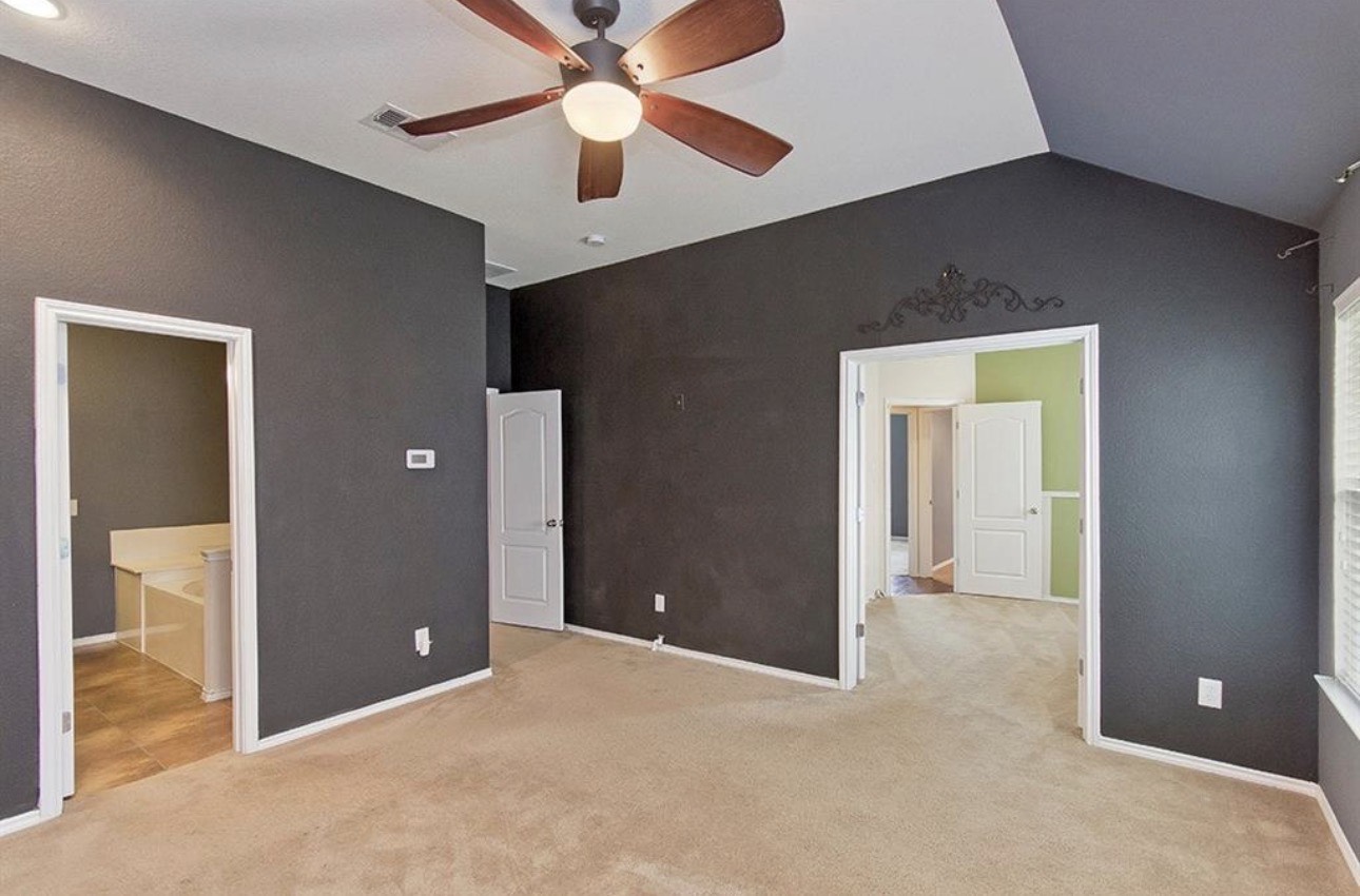 1052 Hot Spring Valley Buda, TX 78610 - Photo 16 of 36 Unfurnished bedroom with vaulted ceiling, ceiling fan, light colored carpet, and ensuite bathroom