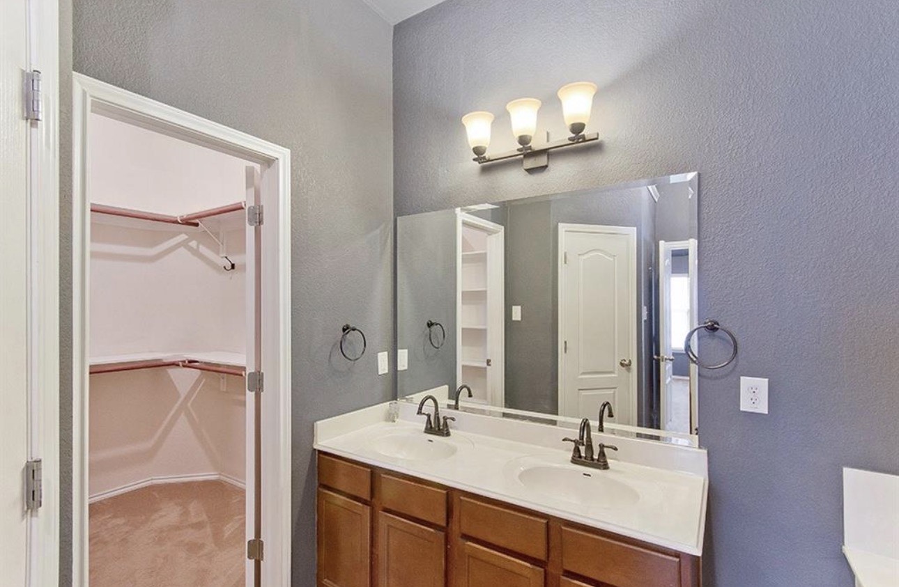 1052 Hot Spring Valley Buda, TX 78610 - Photo 19 of 36 Bathroom featuring a textured wall, double vanity, and a spacious closet