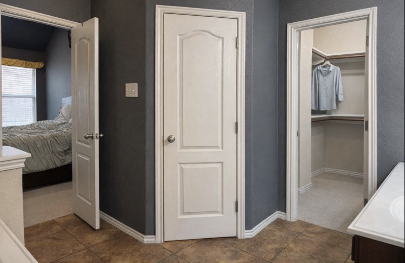 1052 Hot Spring Valley Buda, TX 78610 - Photo 20 of 36 Bathroom featuring double vanity, a walk in closet, and dark colored carpet